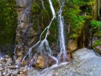 Schmale Wasserfälle gabeln sich an bemoosten Felswänden